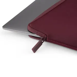 Housse Pipetto Classic Fit bordeaux pour MacBook, avec fermeture zippée, présentée partiellement ouverte autour d’un ordinateur portable argenté.