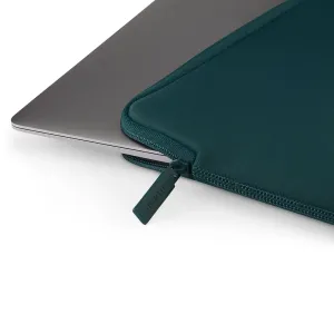Housse Pipetto Classic Fit pour MacBook, bleu sarcelle foncé, avec fermeture éclair, recouvrant partiellement un ordinateur portable argenté.