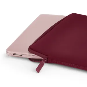Pipetto genomskinligt hardcase till en MacBook Air, delvis instoppat i ett vinrött fodral med dragkedja